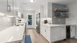 Une cuisine moderne avec des armoires blanches, des appareils en acier inoxydable et un tapis bleu.