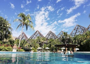 Un área de piscina con palmeras y un cielo azul despejado.