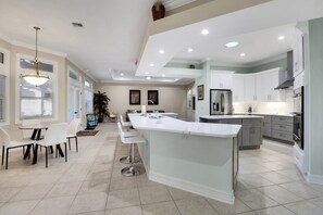 A spacious kitchen with a central island, white cabinetry, and modern appliances.