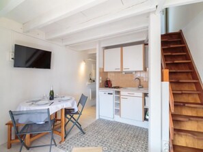 Una cocina compacta con armarios blancos, horno empotrado y una escalera de madera.