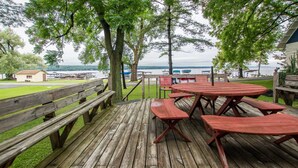 Une terrasse en bois avec des tables de pique-nique et des bancs donnant sur un lac.