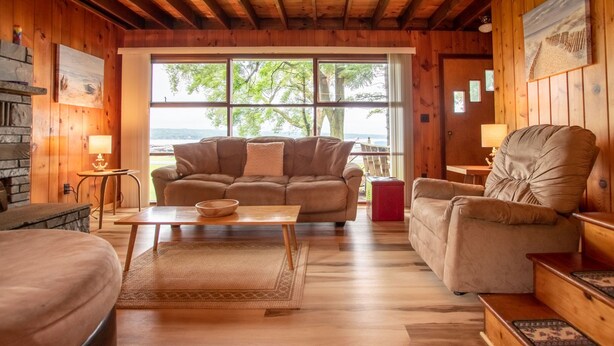 L’intérieur d’un chalet accueillant, avec un canapé, un fauteuil et une table à manger.