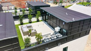 Eine Dachterrasse mit Sitzgelegenheiten im Freien, Topfpflanzen und Blick auf die umliegenden Gebäude.