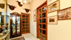 Um corredor com portas de madeira, quadros nas paredes e um armário de vidro com objetos dentro.