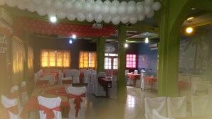 A banquet hall with tables set for a formal event, adorned with white and red decorations.