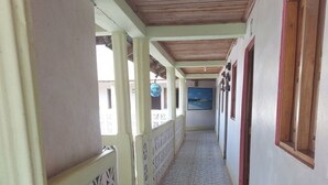 A corridor with patterned tiled flooring, wooden ceiling beams, and a decorative railing.