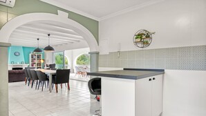 A modern kitchen with a central island, white cabinetry, and a tiled backsplash.