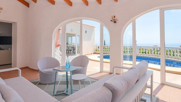 A spacious balcony with a pool, white furniture, and a view of the sea. - Casa La Perla: Villa with Sea View, Pool, Balcony, A/C & Wi-Fi (Benitachell)