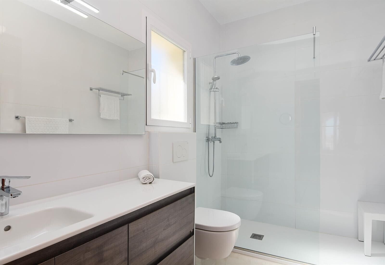 Une salle de bain moderne avec une douche à parois de verre, un lavabo blanc et des toilettes.