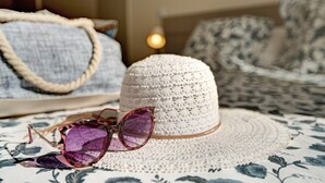 A woven hat, a pair of sunglasses, and a woven bag on a patterned tablecloth.
