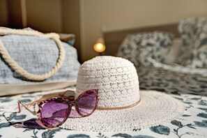 Un chapeau tressé, une paire de lunettes de soleil et un sac tressé, le tout posé sur une nappe à motifs.