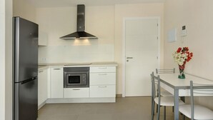 A compact kitchen with a refrigerator, oven, microwave, and a stainless steel range hood. - Apartment Albamar 1D with Mountain View, Wi-Fi, A/C & Balcony (Puerto de Mogán)
