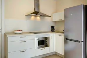 Een moderne keuken met witte kasten, een roestvrijstalen oven, een ingebouwde magnetron en een koelkast.