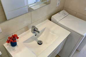 Une salle de bain avec un lavabo blanc, un miroir et des toilettes.
