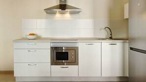 A modern kitchen with a built-in oven, stainless steel appliances, and a white tile backsplash. -  Apartment Albamar 1A with Mountain View, Wi-Fi, A/C, Balcony & Terrace (Puerto de Mogán)