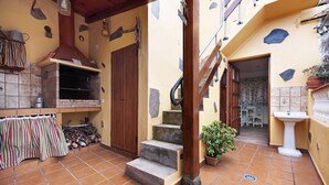 A courtyard with a stone staircase, a wooden door, a tiled floor, a brick oven, and a small garden area. - Vacation Home 'El Lagar' with Mountain View, Shared Terrace and Wi-Fi (Los Silos)