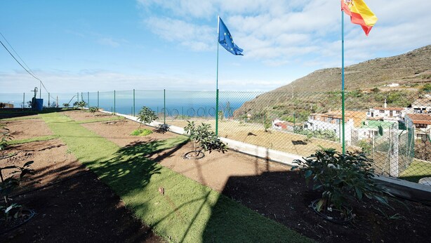 A fenced outdoor area with a view of the sea, a flag, and a hilly landscape in the background. - Vacation Home 'El Lagar' with Mountain View, Shared Terrace and Wi-Fi (Los Silos)