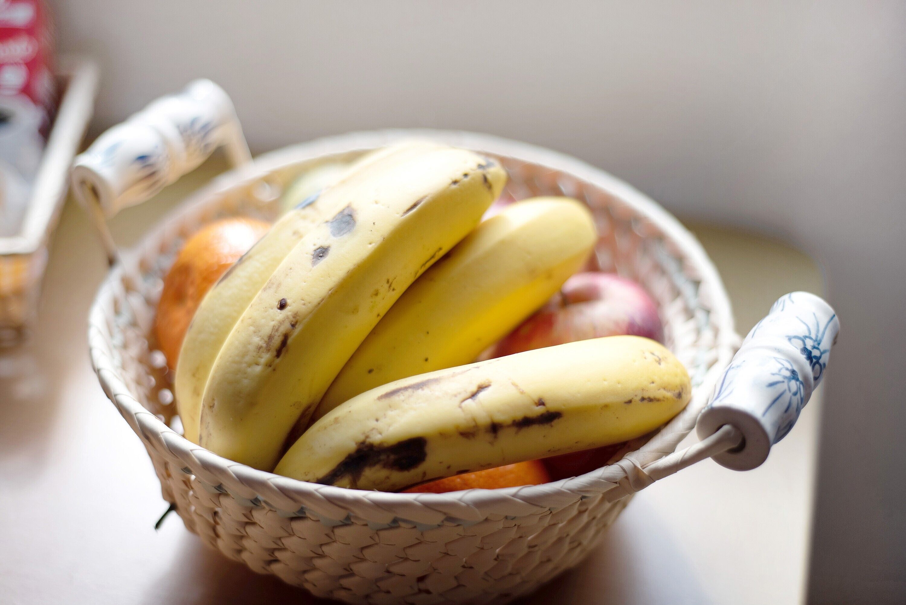 A woven basket containing bananas and oranges.