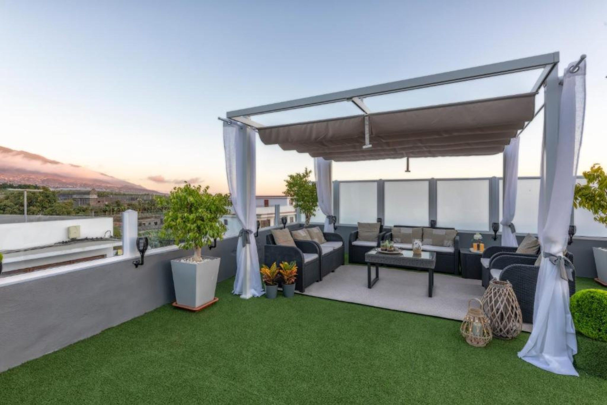 Eine Dachterrasse mit Außenmöbeln, einer Pergola und Blick auf die Stadtlandschaft.
