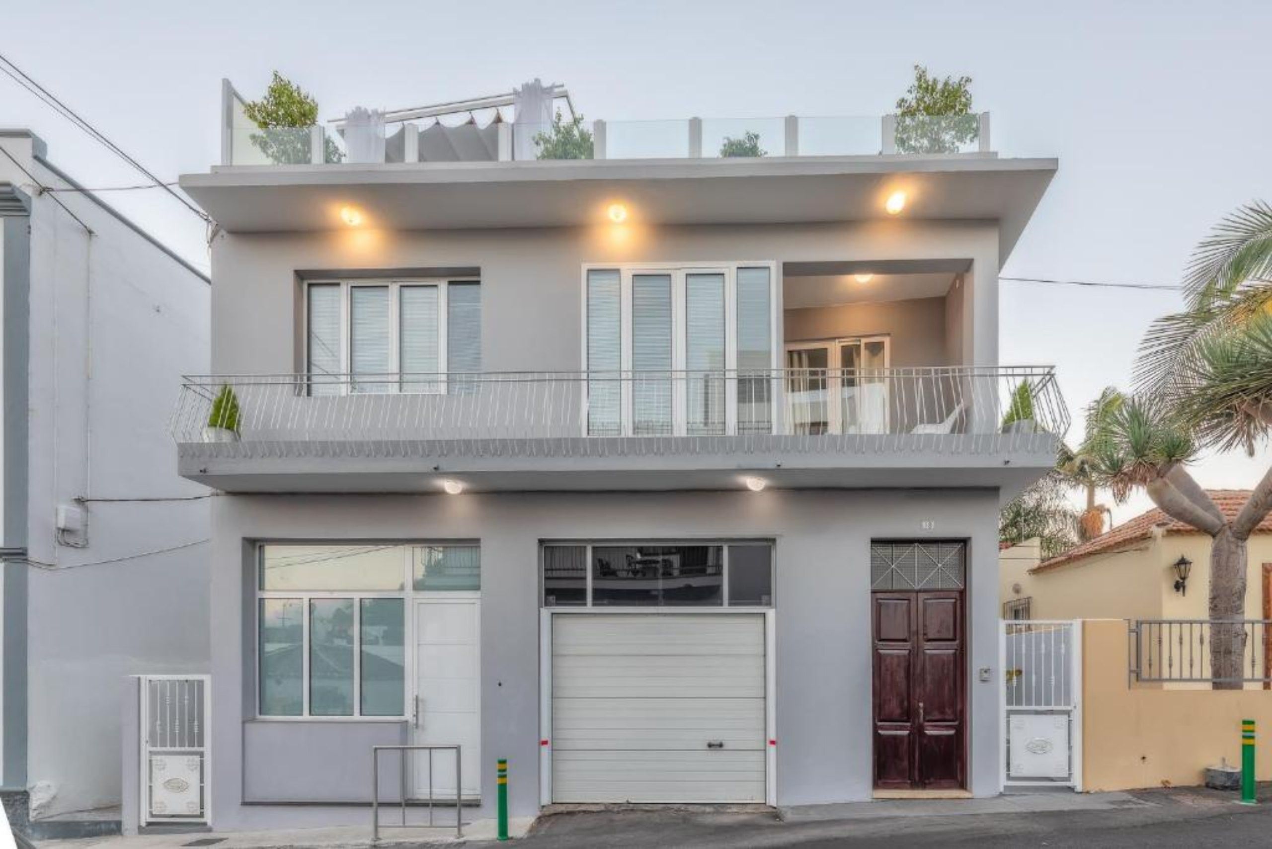 Een woonhuis met twee verdiepingen, een balkon, grote ramen en een garage.