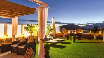 An outdoor patio with a dining area, lounge chairs, and a view of the mountains.