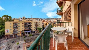 A balcony with a table and chairs, overlooking a cityscape with buildings and a clear sky. - Vacation Apartment in Central Fuengirola with Balcony, Air Conditioning, and WiFi (Fuengirola)