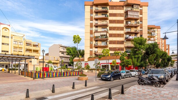 A multi-story residential building with balconies, a pedestrian crossing, and parked cars. - Vacation Apartment in Central Fuengirola with Balcony, Air Conditioning, and WiFi (Fuengirola)