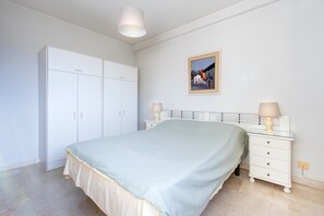 Une chambre à coucher comprenant un lit, une armoire, une table de chevet avec une lampe et un tableau encadré accroché au mur.