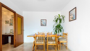 A dining area with a wooden table and chairs, a potted plant, and framed pictures on the wall. - Vacation Apartment in Central Fuengirola with Balcony, Air Conditioning, and WiFi (Fuengirola)