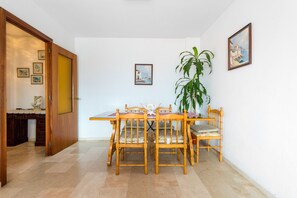 Un coin repas avec une table et des chaises en bois, une plante en pot et des tableaux encadrés accrochés au mur.