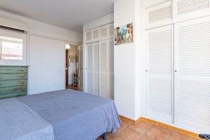 A bedroom with a bed, a dresser, and a closet with louvered doors.
