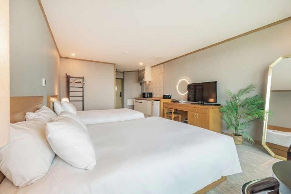 Une chambre d’hôtel avec deux lits, un bureau avec un ordinateur, une télévision et un miroir.