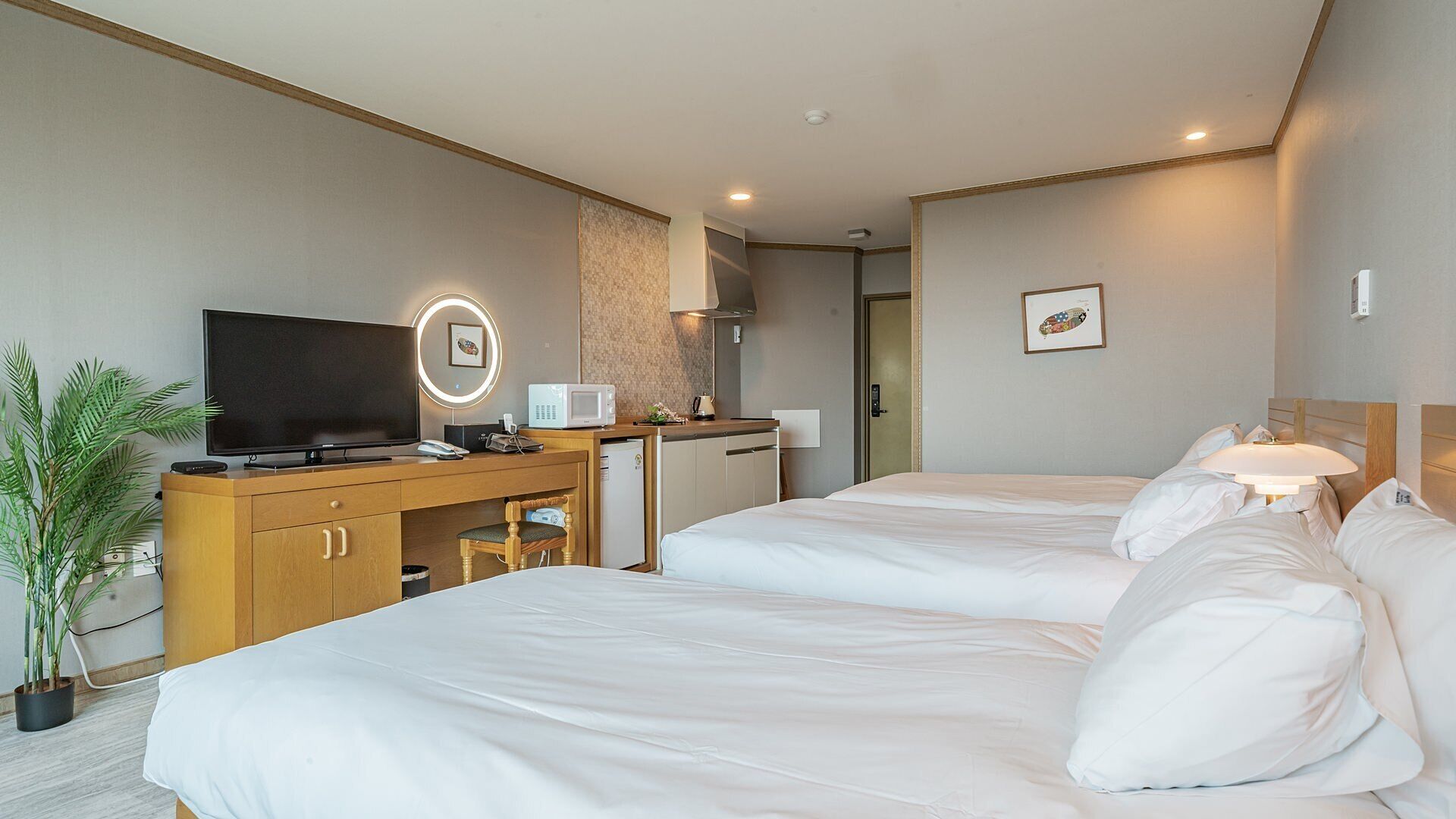 Een hotelkamer met twee bedden, een bureau met televisie, een magnetron en een kleine kitchenette.