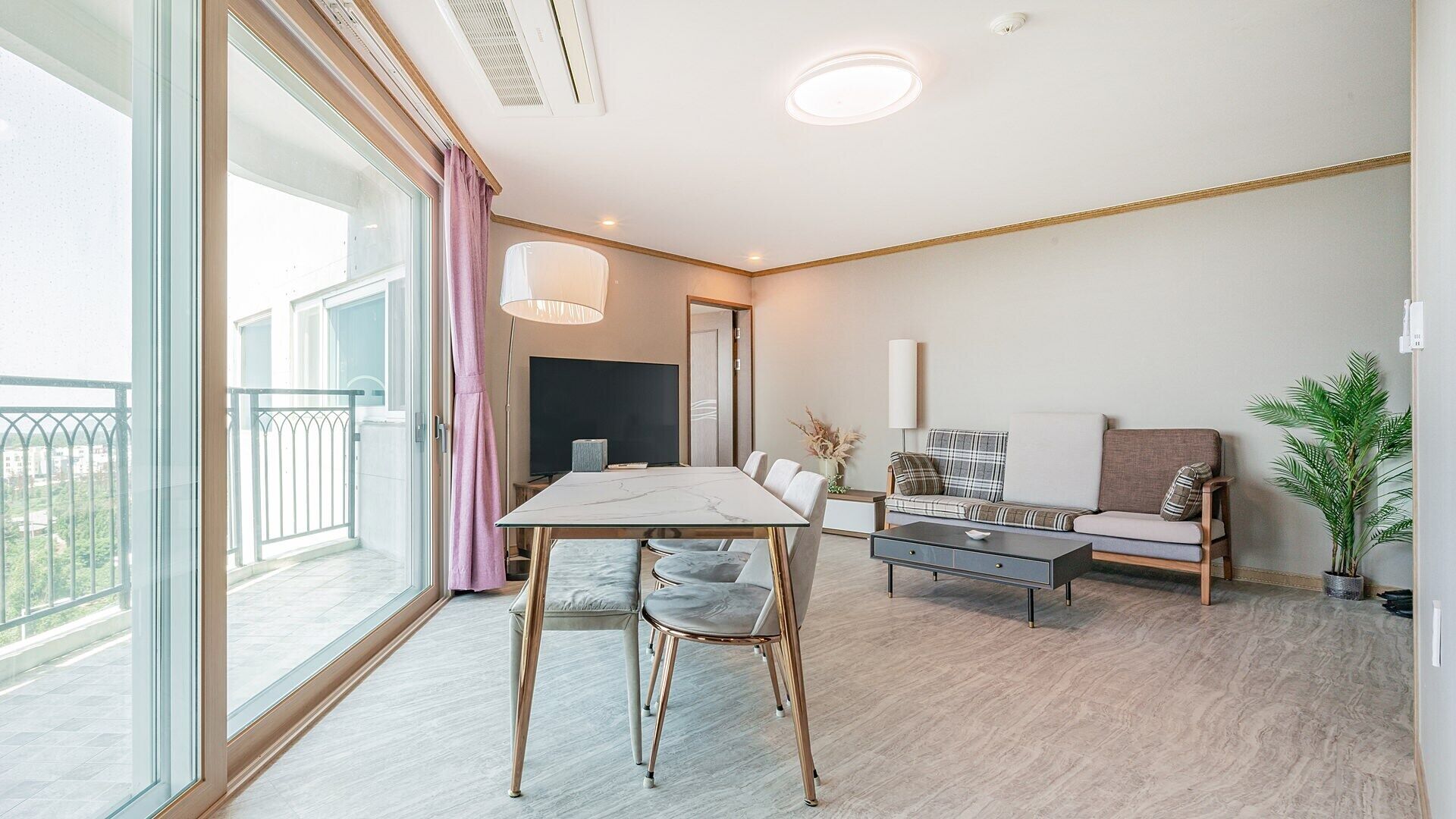 A modern living room with a dining table, sofa, and TV.