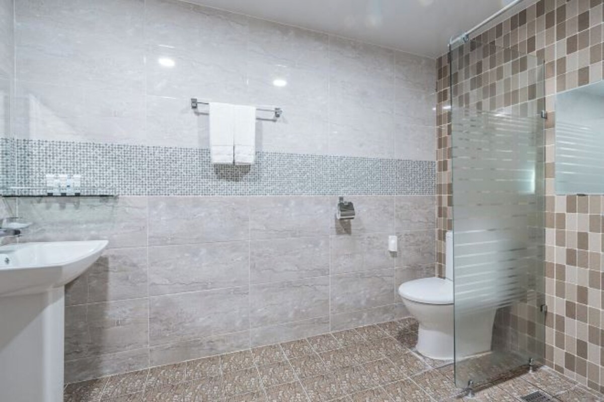 Une salle de bain avec une douche à parois de verre, un lavabo blanc et des toilettes.