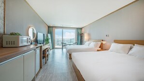 Habitación de hotel con cama, escritorio con microondas, televisión y balcón con vistas.