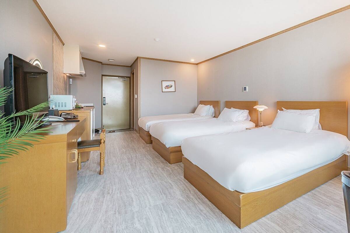 Een hotelkamer met twee bedden, een bureau met een computer, een stoel en een lamp.