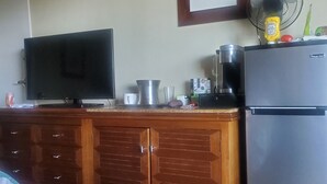 A kitchenette with a refrigerator, microwave, coffee maker, and a flat-screen TV. - KAUA'I BEACH RESORT-BEACHFRONT, OCEAN VIEW, POOLSIDE VIEW FROM YOUR LANAI (Lihue)