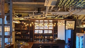 Un espace bar avec un comptoir, des tabourets et un réfrigérateur.