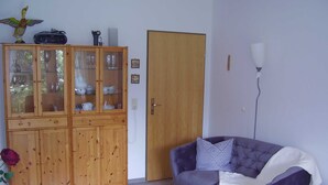 Ein Wohnzimmer mit einem violetten Sofa, Holzschränken, einer Tür und einer Stehlampe.