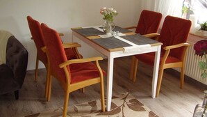 Ein Essbereich mit einem weißen Tisch, roten Stühlen und einer Vase mit Blumen.