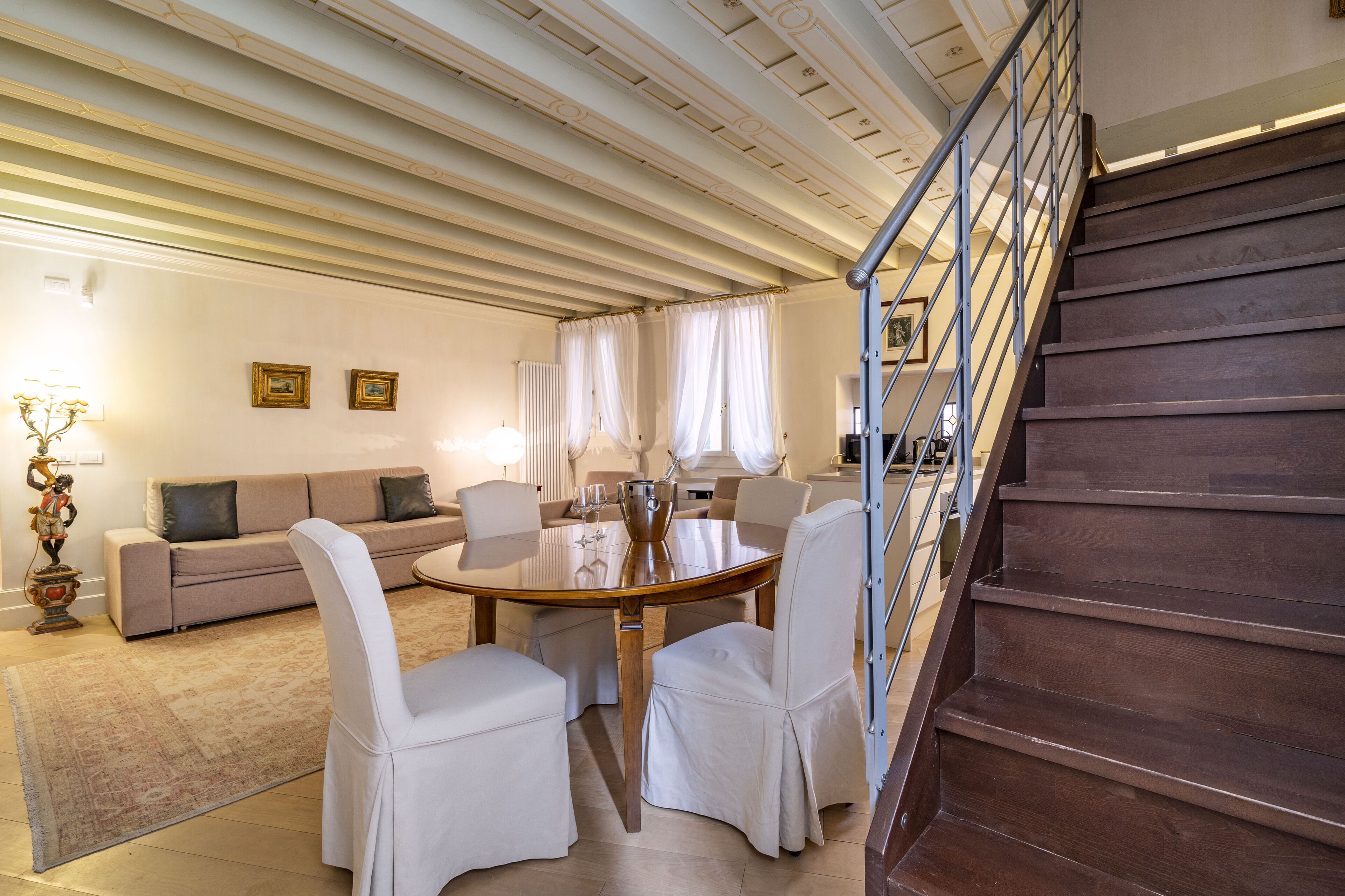 Un coin repas avec une table ronde, des chaises blanches et un escalier.