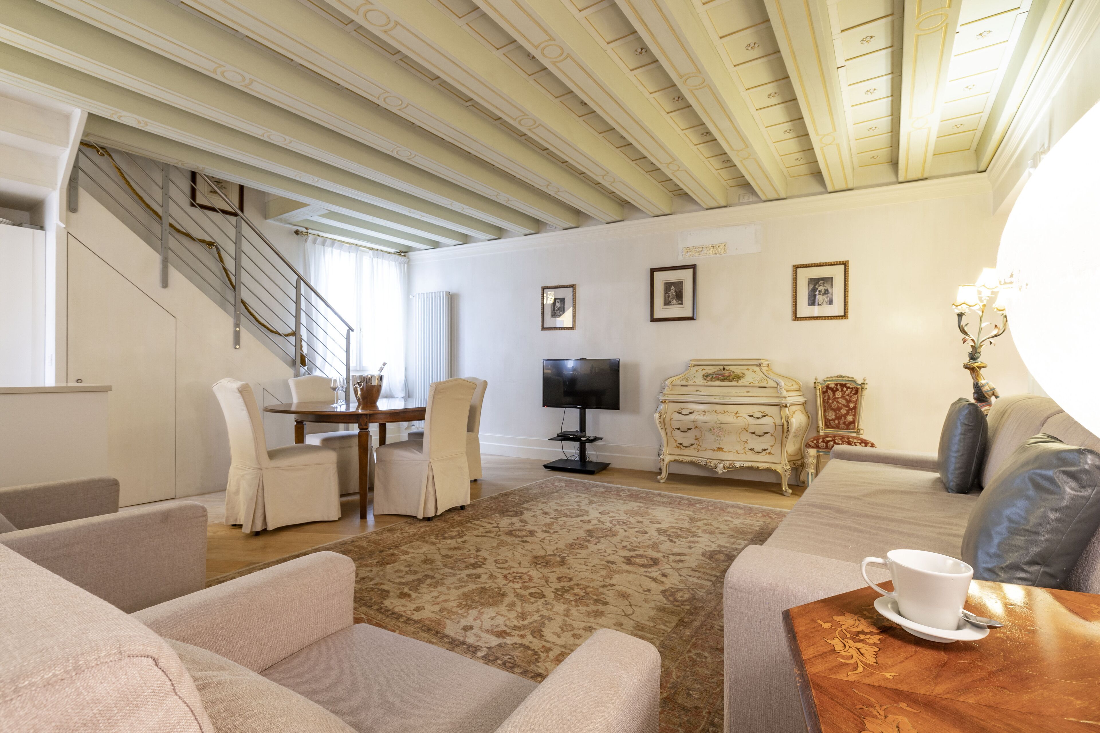 A living room with a staircase, a television, a dining area, and a sofa.