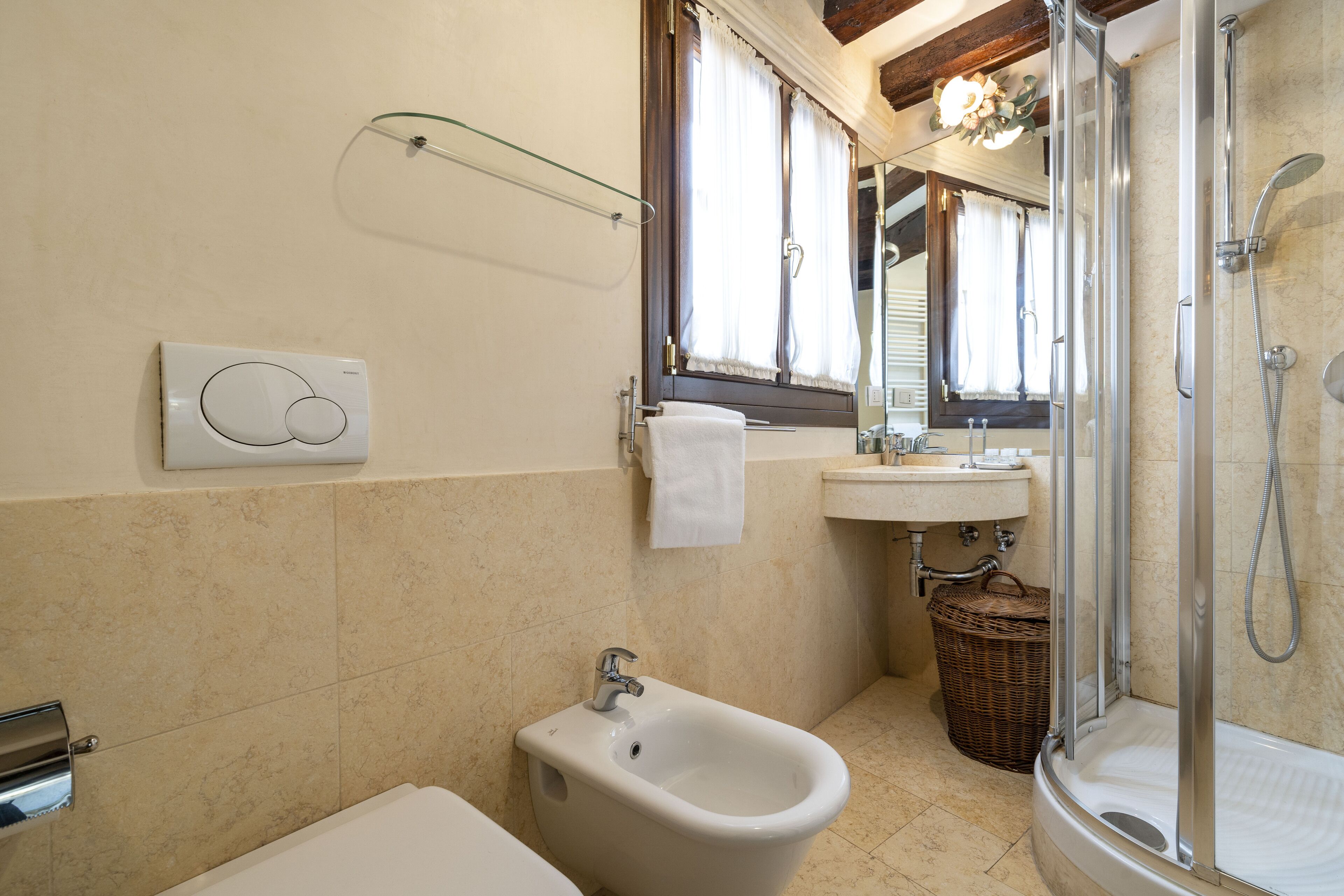 Een badkamer met een toiletbrons, wastafel, spiegel en douche.