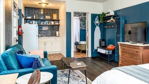 Un espacio habitable compacto con kitchenette, un sofá, una cama y un televisor.