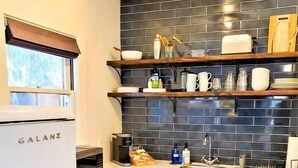 Una cocina compacta con armarios blancos, un salpicadero de azulejos negros y un refrigerador Galanz.