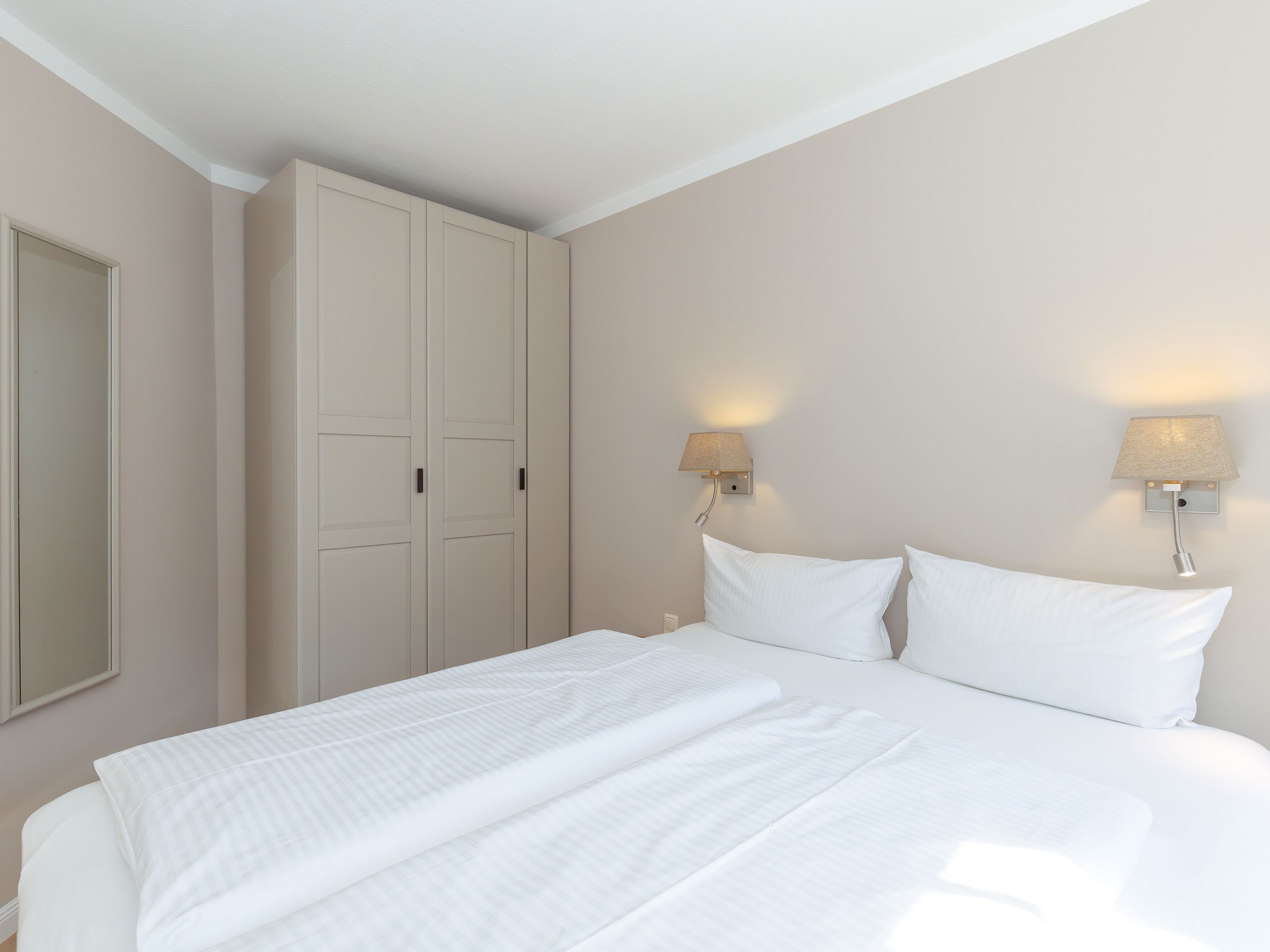 Habitació d'hotel amb un llit, un armari i dues làmpades penjades a la paret.