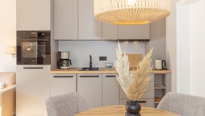 Eine moderne Küche mit Einbauofen, Kaffeemaschine und Essbereich mit rundem Tisch und zwei Stühlen.