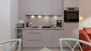 Cocina moderna con horno empotrado, cafetera y hervidor sobre la encimera.