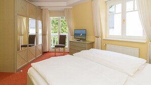 Een hotelkamer met een bed, een televisie, een stoel en een raam met gordijnen.